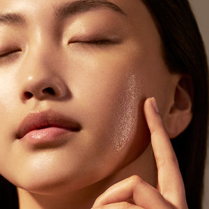 Ženska, ki kaže svetleče gladko lice - L’Occitane