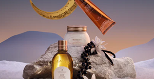 L'Occitane izdelki praznične kolekcije  Nuit Festive obdani s sceno snega, lune in belih gor v ozadju