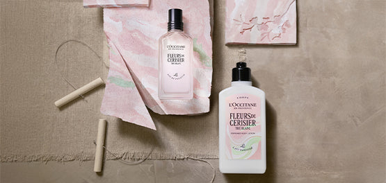Izdelki L’Occitane kolekcije Fleurs de Cerisier Thé Blanc, postavljeni na marmoriano glino v nežno roza barvi.  
