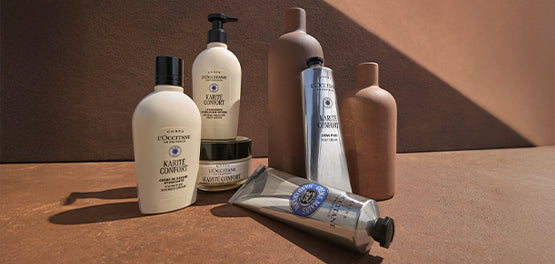 Izdelki iz L'Occitanove kolekcije za nego suhe kože na telesu na glinenem ozadju