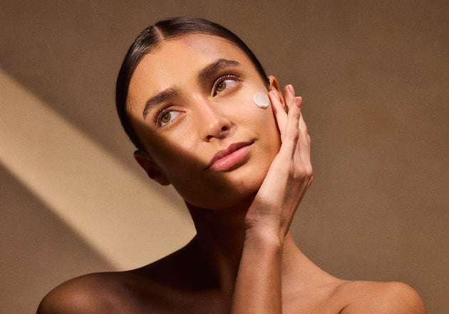 Ženska si na obraz nanaša karitejeo maslo za nego obraza L'Occitane