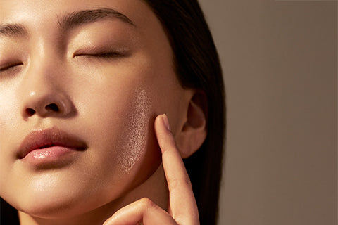 Ženska, ki kaže svetleče gladko lice - L’Occitane