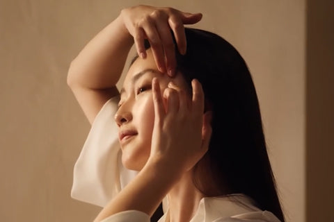 Ženska, ki kaže postopek masiranja obraza in nanašanja produkta - L'Occitane.