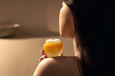 Ženska, ki drži na rami Božanska krema za obraz - L'Occitane.