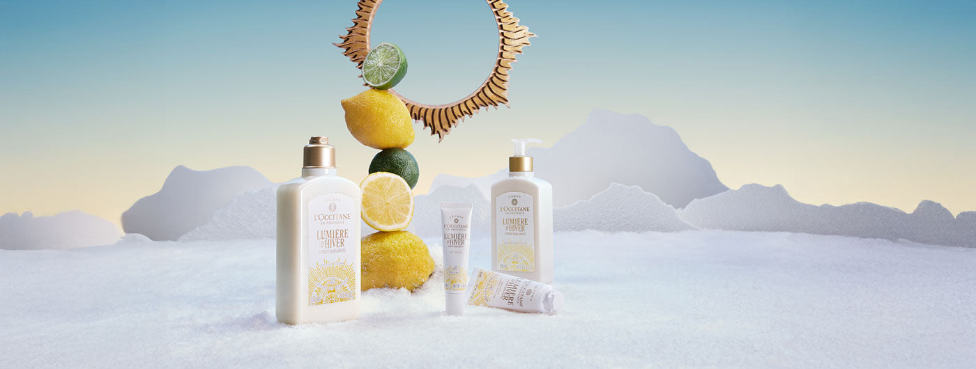 L'Occitane izdelki praznične kolekcije Lumière d’Hiver obdani s sceno snega, citrusov in belih gor v ozadju
