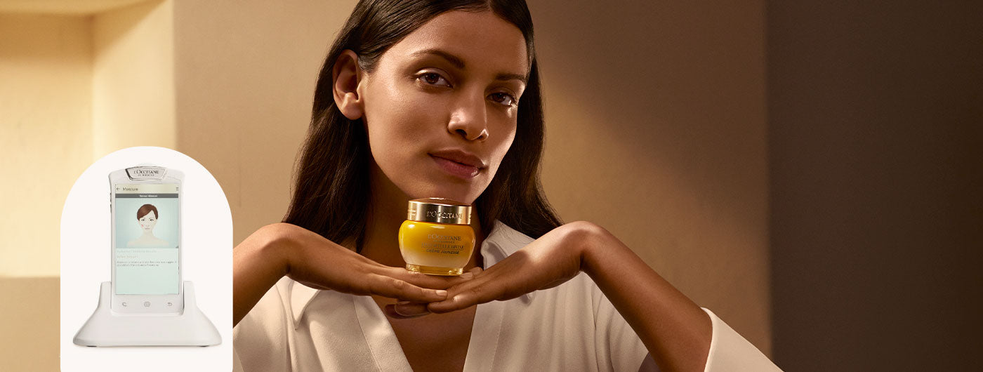 Ženska v rokah drži L'Occitane Božanska krema za obraz.