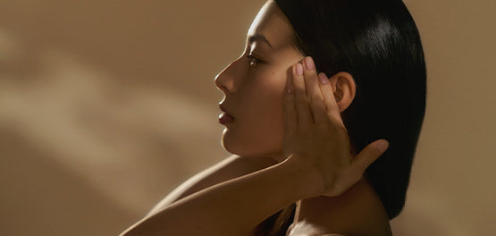 Ženska, ki se z rokami dotika kože ob ušesih - L'Occitane.