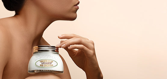 Ženska, ki v naročju drži Mandljevo koncentrirano mleko - L'Occitane.