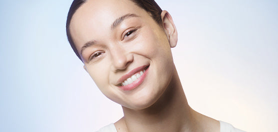 Obraz nasmejane ženske s sijočo kožo, ki jo neguje z izdelki L'Occitane 