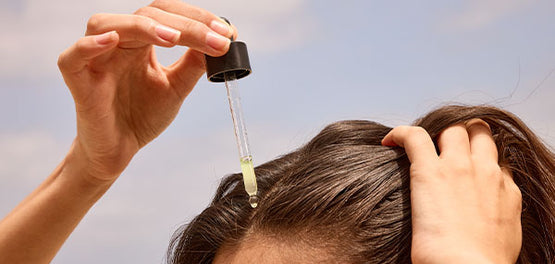 Ženska si na lasišče s kapalko nanaša L'Occitanov serum za lase 