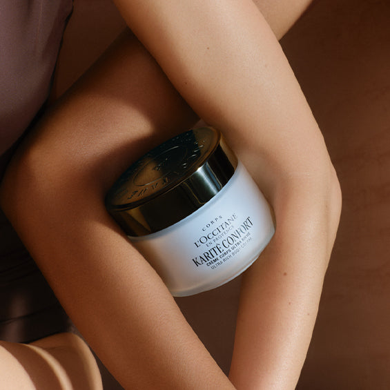 Ženske roke objemajo Ultrabogato kremo za telo Karite  