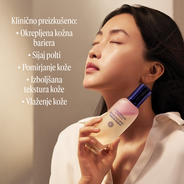 Ženska, ki ob obrazu drži izdelek L’Occitane Trifazna esenca za obraz - Immortale Reset kolekcija.