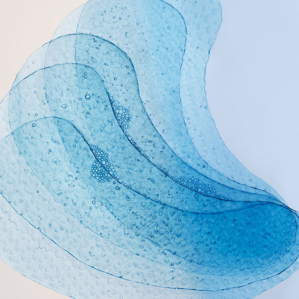 Pet žlahtnih obližev za kožo pod očmi znamke L'Occitane naloženih eden na drugega in fotografiranih od blizu