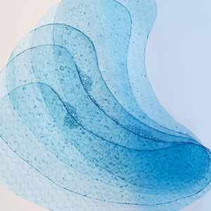 Pet žlahtnih obližev za kožo pod očmi znamke L'Occitane naloženih eden na drugega in fotografiranih od blizu