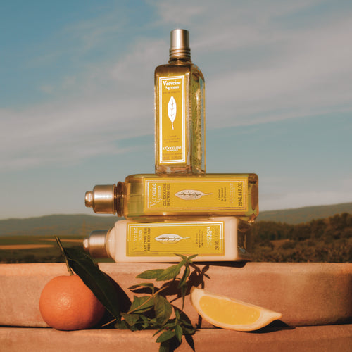 Tri Geli za prhanje Citronka L'Occitane, obsijani s sončnim zahodom in obdani s citrusi