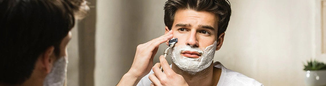 Moški si z britvico in L'Occitane izdelki brije brado 